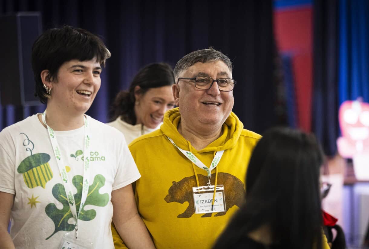 A woman and man stand together smiling amogst a crowd at a community harvest festival event